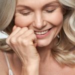 Happy cute shy middle aged woman laughing. Anti age face skin care, closeup view